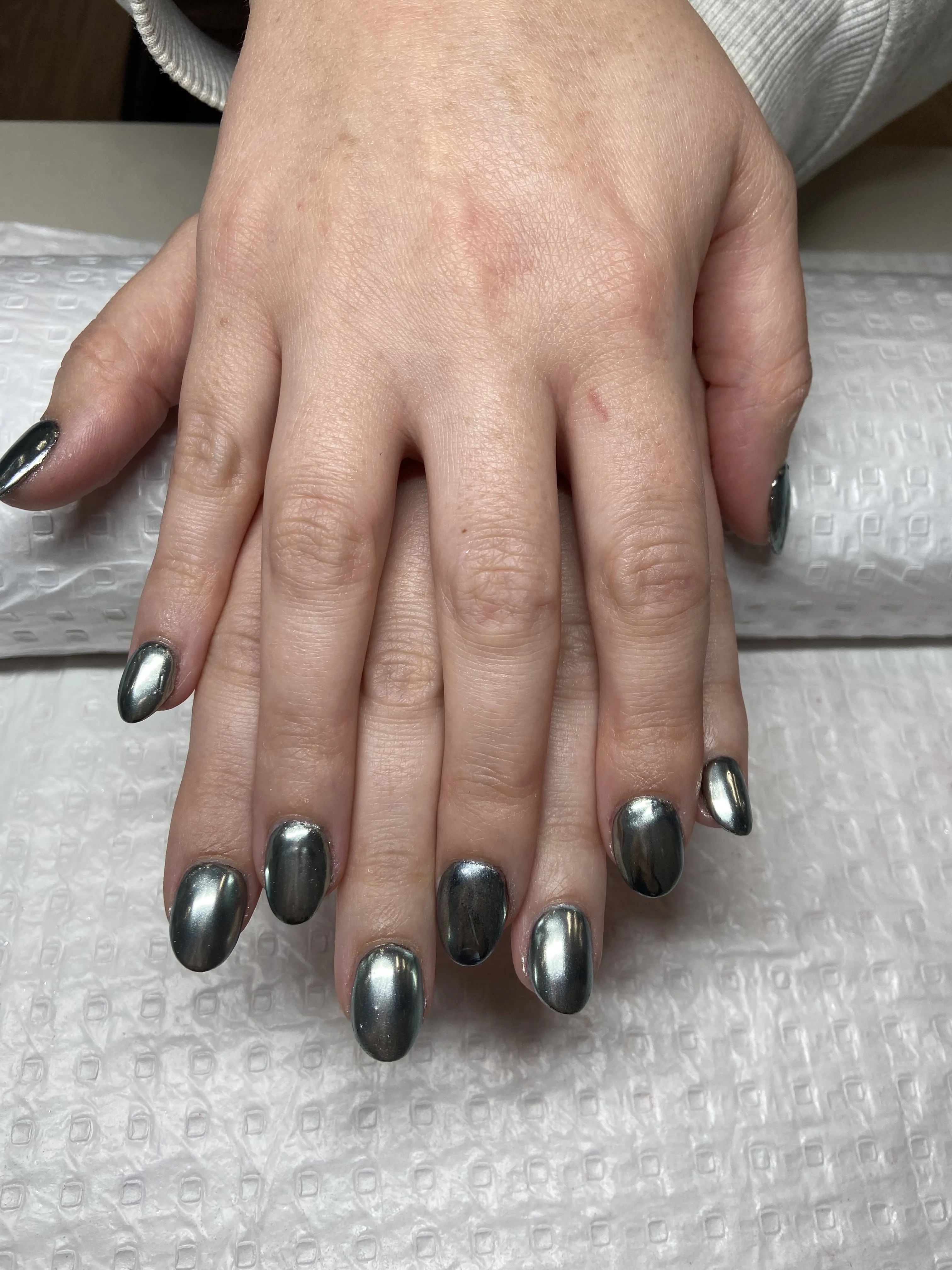 Graphite and silver chrome oval nails on a white salon towel
